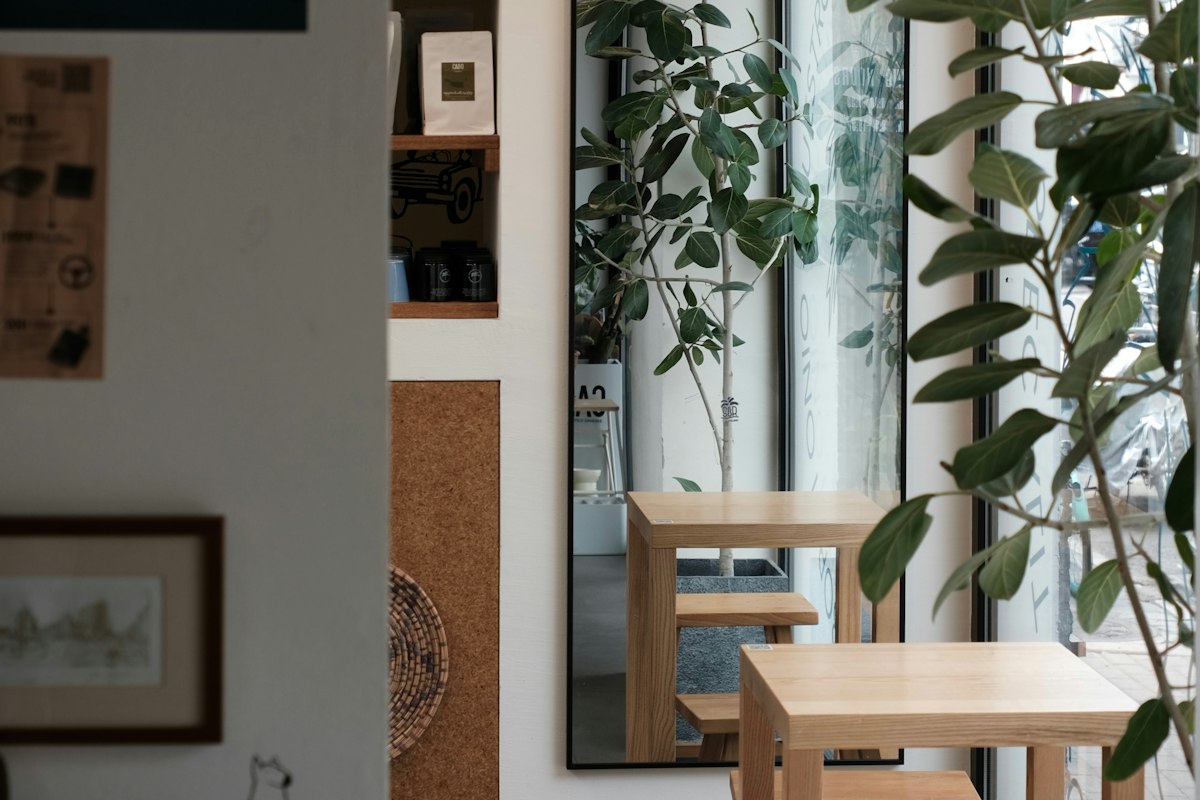 観葉植物と木のテーブルのある明るい店内(Unsplashの写真)